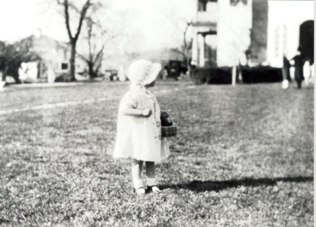 Getting ready for the egg hunt. Little girl wearing a bonnet and holding a basket.
