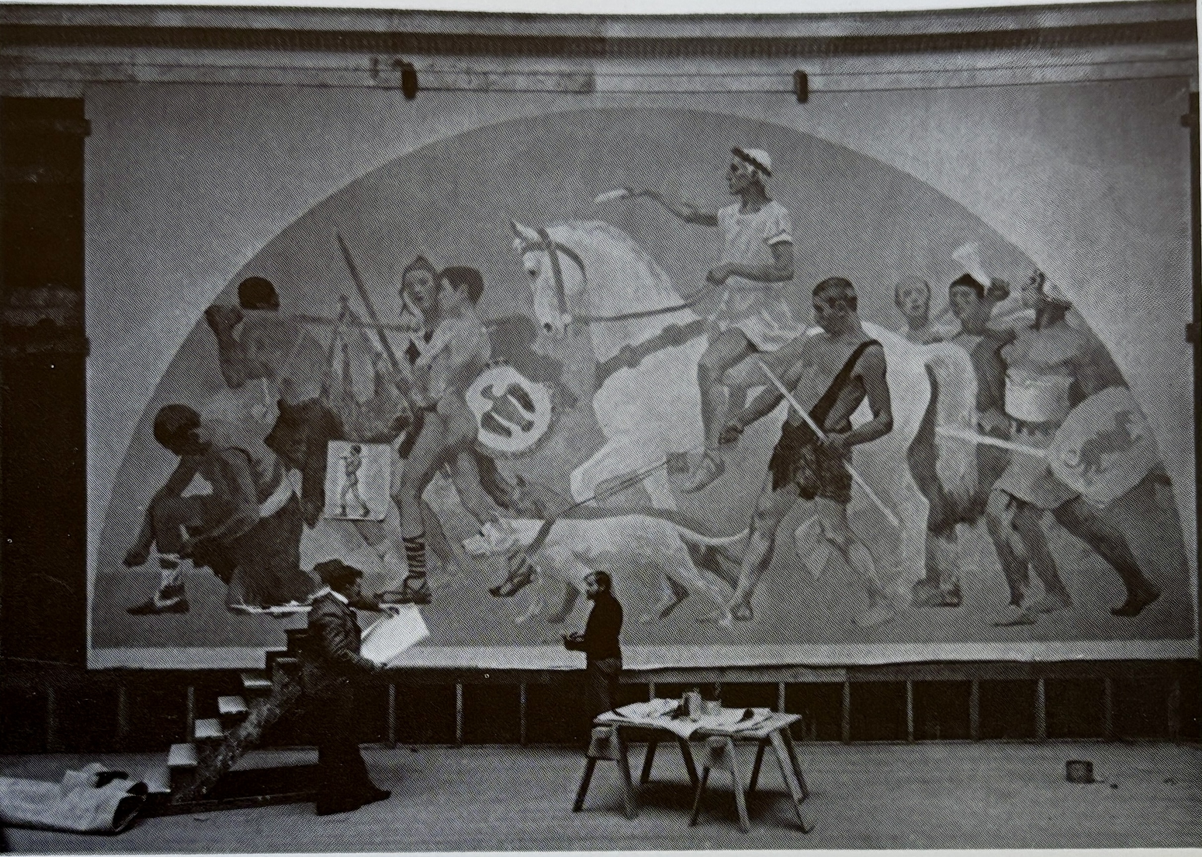 two men standing in front of large mural